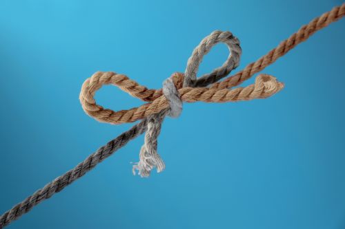 Foto: Two ropes, gray and brown, tied together in a bow